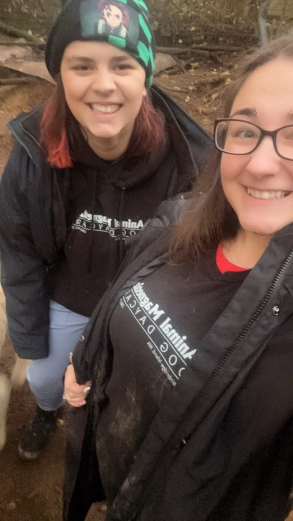 Two young women in black jackets and t-shirts from Animal Magnetism, smiling at the camera.